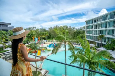a woman in a hat standing on a balcony looking at a pool at Wyndham La Vita Rawai Phuket in Rawai Beach