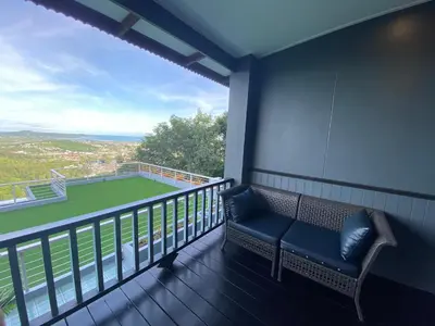 a balcony with a bench and a tennis court at Phuket View Coffee and Resort in Chalong