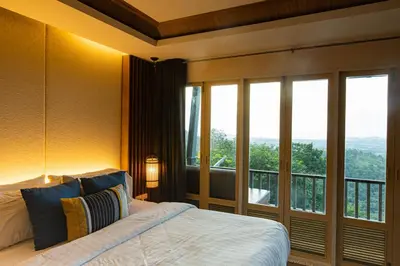a bedroom with a bed and a large window at Phuket View Coffee and Resort in Chalong