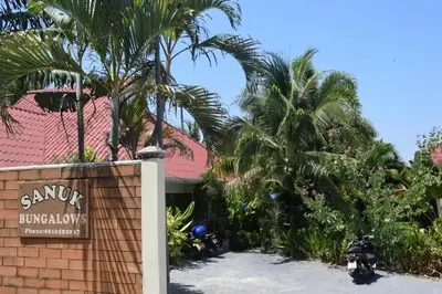 a sign in front of a building with palm trees at Sanuk bungalows in Rawai Beach