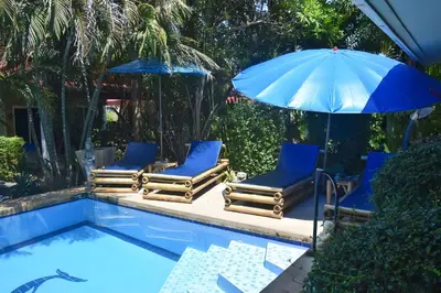 a group of chairs and an umbrella next to a swimming pool at Sanuk bungalows in Rawai Beach
