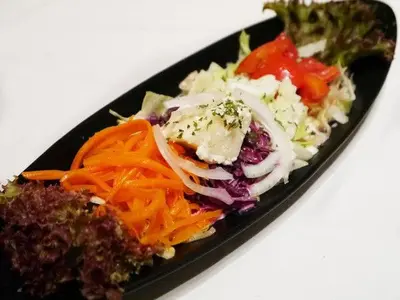 a black plate of food with vegetables on a table at Tolmaj Family Apartment in Ao Nang Beach