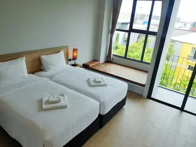 a bedroom with two beds and a large window at Atom Phuket Hotel in Nai Yang Beach