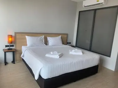a bedroom with a bed with two white towels on it at Atom Phuket Hotel in Nai Yang Beach