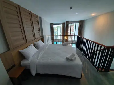 a bedroom with a white bed and a balcony at Atom Phuket Hotel in Nai Yang Beach