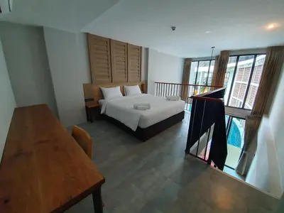 a bedroom with a bed and a table in a room at Atom Phuket Hotel in Nai Yang Beach