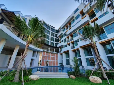 a building with palm trees in front of it at Atom Phuket Hotel in Nai Yang Beach