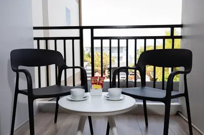 two black chairs and a table with cups on it at The Bell Airport Phuket Hotel - SHA Extra Plus in Nai Yang Beach