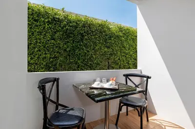 a table and two chairs on a balcony with a hedge at The Bell Airport Phuket Hotel - SHA Extra Plus in Nai Yang Beach