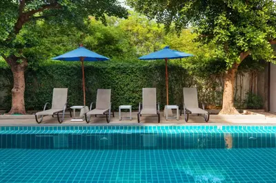 a group of chairs and umbrellas next to a pool at The Bell Airport Phuket Hotel - SHA Extra Plus in Nai Yang Beach