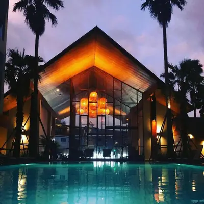 a building with a pool in front of a building with palm trees at PALMYRAH SURIN, MODERN 1BR with Terrace, 150 meters to Surin Beach in Surin Beach