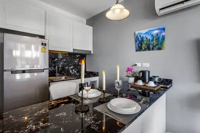 a kitchen with white cabinets and a black counter top at PALMYRAH SURIN, MODERN 1BR with Terrace, 150 meters to Surin Beach in Surin Beach