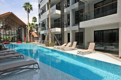 a swimming pool with lounge chairs next to a building at The Sea View room in Palmyrah Surin by Holy Cow in Surin Beach