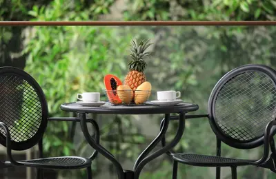 a table with a pineapple and cups and chairs at The Palmyrah Surin by Holy Cow, 1-BR, courtyard or pool view in Surin Beach