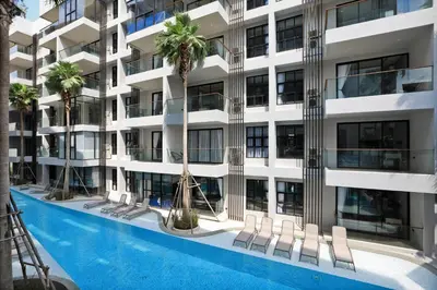 an apartment building with a swimming pool and palm trees at The Palmyrah Surin by Holy Cow, 1-BR, courtyard or pool view in Surin Beach