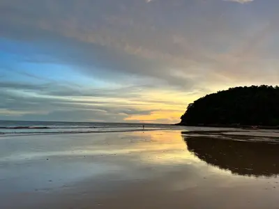 a beach with a person walking on the sand at Bangtao Rooms in Bang Tao Beach