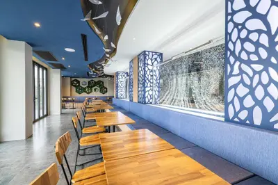 a row of wooden tables and chairs in a restaurant at Kana Triple L Hotel Phuket\u666e\u5409\u5c9b\u5361\u5a1c3L\u9152\u5e97 in Patong Beach