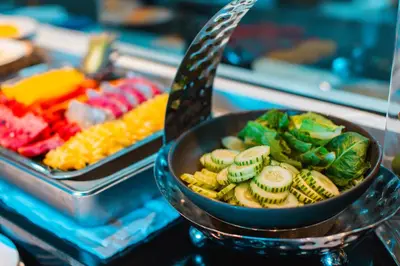 a bowl of vegetables and a pan of other food at Kana Triple L Hotel Phuket\u666e\u5409\u5c9b\u5361\u5a1c3L\u9152\u5e97 in Patong Beach