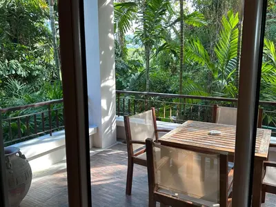 a table and chairs on a balcony with trees at Kata Gardens Luxury Apartment 8A at Kata Noi Beach in Kata Beach