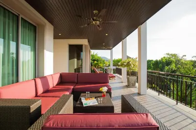 a patio with red couches and a table on a balcony at Ocean views Kata gardens penthouse 6C near Kata Noi Beach in Kata Beach