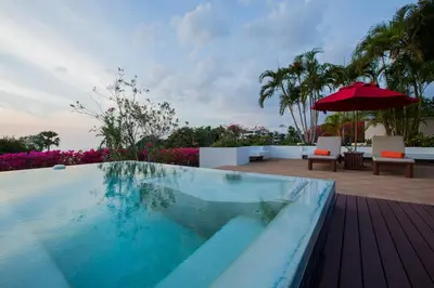 a swimming pool with an umbrella on a deck at Ocean views Kata gardens penthouse 6C near Kata Noi Beach in Kata Beach