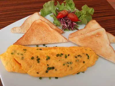 a white plate topped with a omelet and a salad at GN Capsule Hostel Patong in Patong Beach