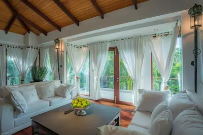 a living room with white furniture and a table with a bowl of fruit at Villa in the Garden, Surin Beach with private spa. in Surin Beach