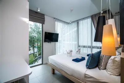 a bedroom with a bed and a large window at Oceanstone Resort by Lofty in Bang Tao Beach