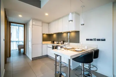 a kitchen with white cabinets and a island with bar stools at Oceanstone Resort by Lofty in Bang Tao Beach