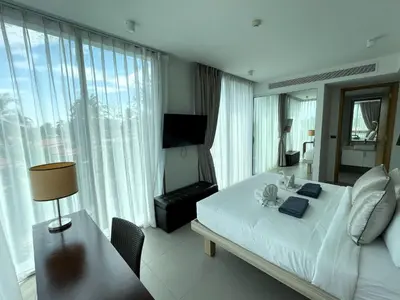 a bedroom with a large white bed and a chair at Oceanstone Resort by Lofty in Bang Tao Beach