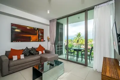 a living room with a couch and a table at Oceanstone Resort by Lofty in Bang Tao Beach