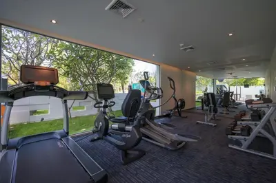 a gym with several treadmills and elliptical machines at Oceanstone Resort by Lofty in Bang Tao Beach