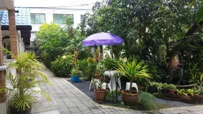a garden with a purple umbrella and potted plants at Wattana Bungalow in Nai Yang Beach