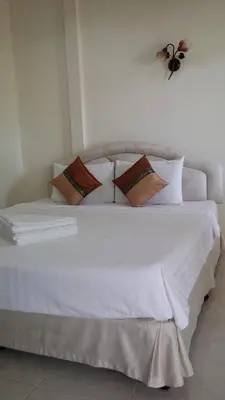 a white bed with pillows and a bee on the wall at Wattana Bungalow in Nai Yang Beach