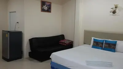a bedroom with a bed and a black chair at Wattana Bungalow in Nai Yang Beach