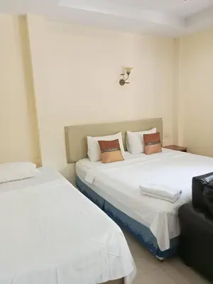 a room with two beds with white sheets and brown pillows at Wattana Bungalow in Nai Yang Beach