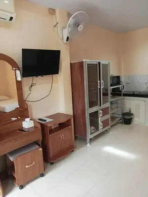 a living room with a television and a desk with a fan at Wattana Bungalow in Nai Yang Beach