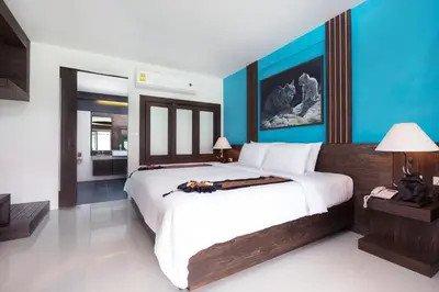 a bedroom with a large bed and blue walls at Naina Resort & Spa - SHA Extra Plus in Patong Beach