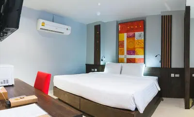 a bedroom with a large white bed and a desk at Naina Resort & Spa - SHA Extra Plus in Patong Beach
