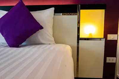 a bed with a purple pillow next to a lamp at Rawai Paradise in Rawai Beach