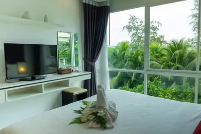 a bedroom with a white bed with a large window at Rawai Paradise in Rawai Beach