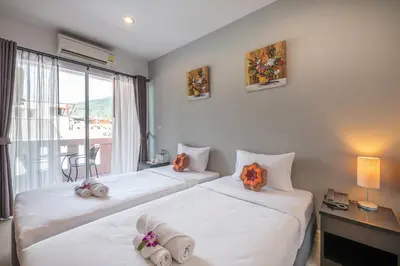 a hotel room with two beds and a window at May House Karon Beach in Karon Beach