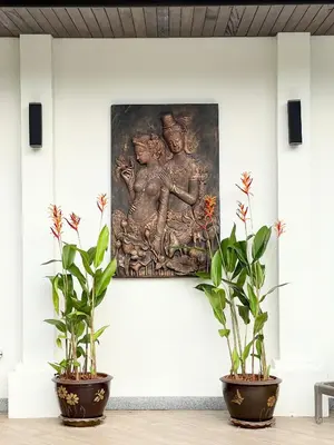 a painting on a wall next to two potted plants at Villa Suksan - Kubu in Nai Harn Beach