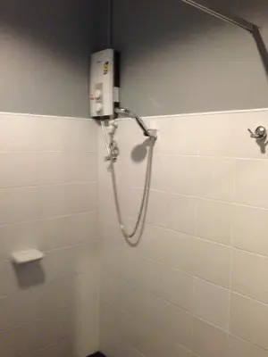 a shower in a bathroom with white tiles at Chalong Sea Breeze in Chalong