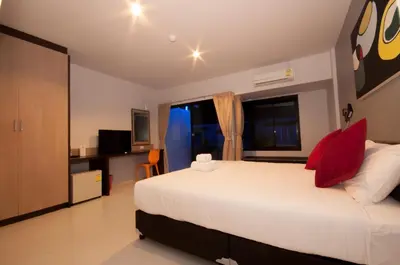 a bedroom with a large white bed with red pillows at Chalong Sea Breeze in Chalong
