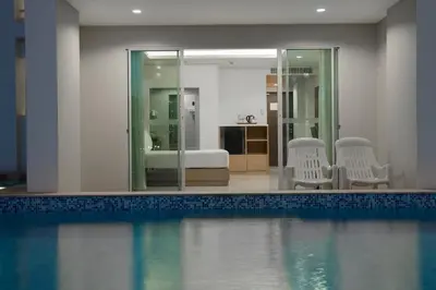 a room with a swimming pool with chairs and a bedroom at Chanalai Hillside Resort, Karon Beach in Karon Beach