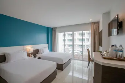 a hotel room with two beds and a window at Chanalai Hillside Resort, Karon Beach in Karon Beach