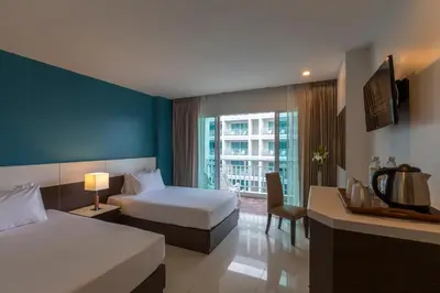 a hotel room with two beds and a television at Chanalai Hillside Resort, Karon Beach in Karon Beach