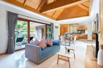 a living room with a blue couch and a table at Lady Naya Villas - SHA Extra Plus in Rawai Beach