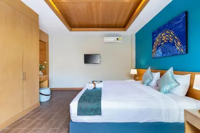 a bedroom with a large bed with a blue wall at Lady Naya Villas - SHA Extra Plus in Rawai Beach